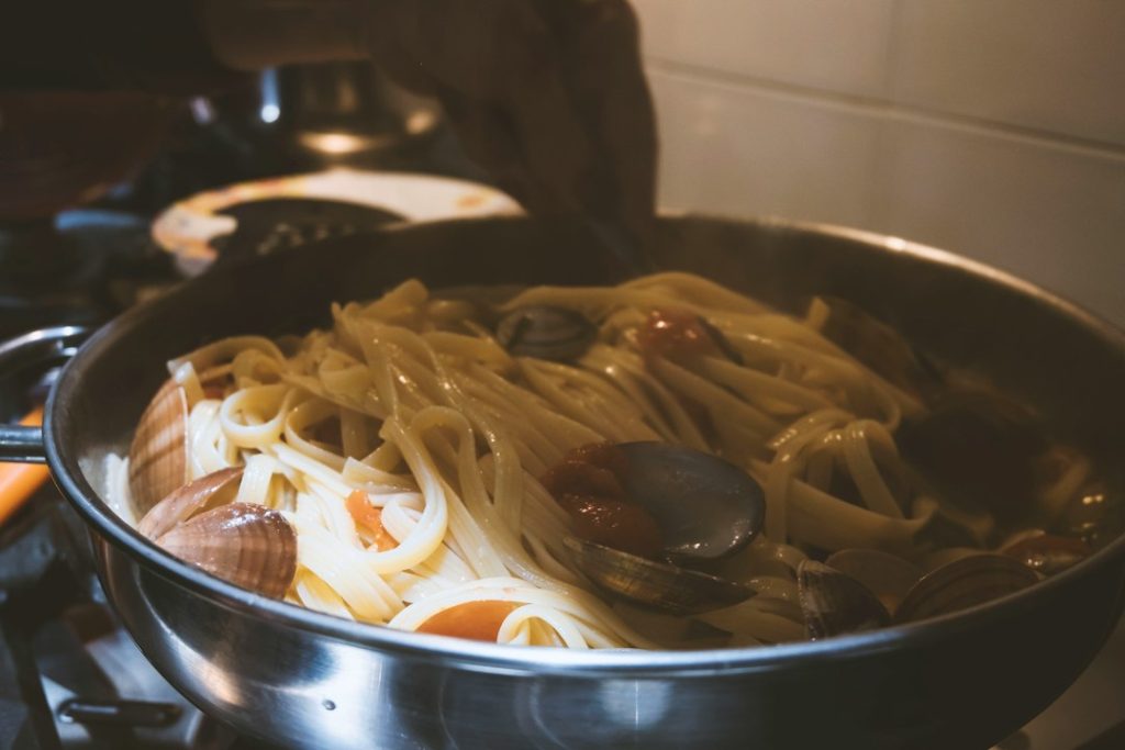 Pasta dengan saus mengilap di dalam wajan, ilustrasi teknik mengikat saus dengan air rebusan pasta